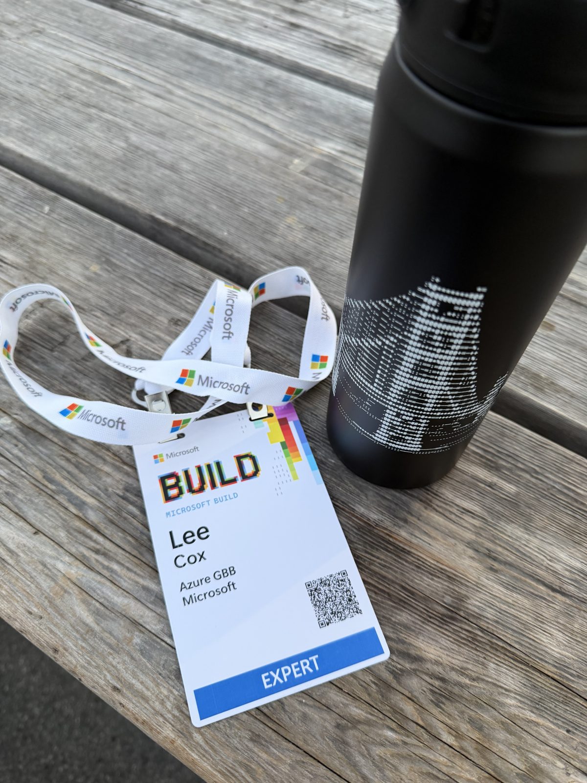 Microsoft Build EXPERT badge for Lee Cox, Azure GBB, next to a black water bottle with the Golden Gate Bridge rendered in ASCII art
